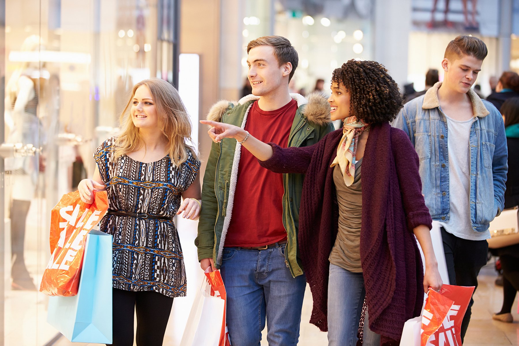 Student walking through shopping centre holding shopping bags